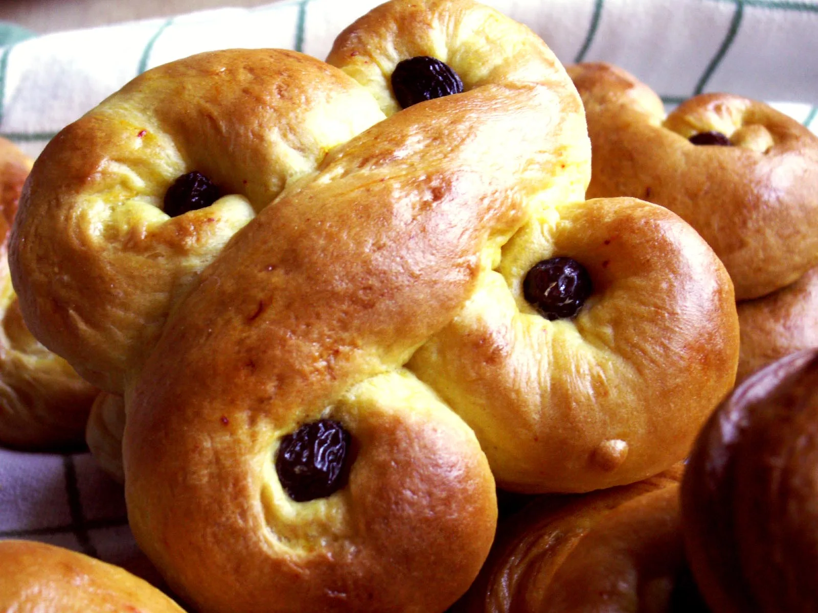 Gyllene saffransbullar i den gamla formen gullvagn, med russin i svängarna, på ett bakplåtspapper