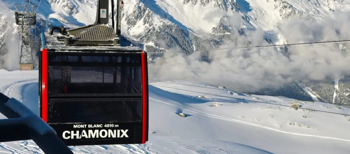 Gondelhutten in Chamonix boven besneeuwde bergen en een bewolkte hemel.