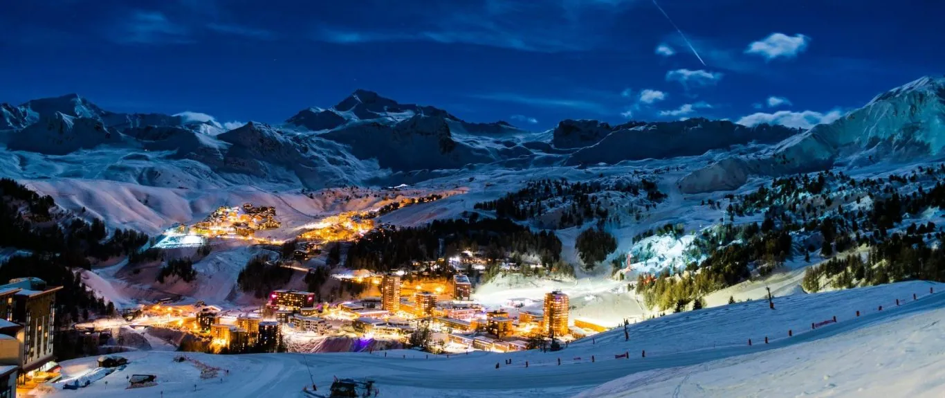 Prachtig besneeuwd berglandschap met verlichte dorpjes onder een sterrenhemel.