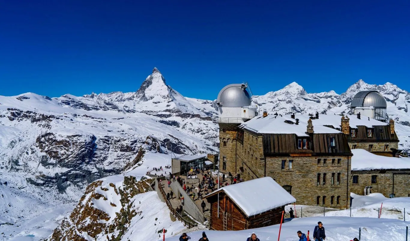 Besneeuwde bergen met de Matterhorn op de achtergrond en een gebouw op de voorgrond.