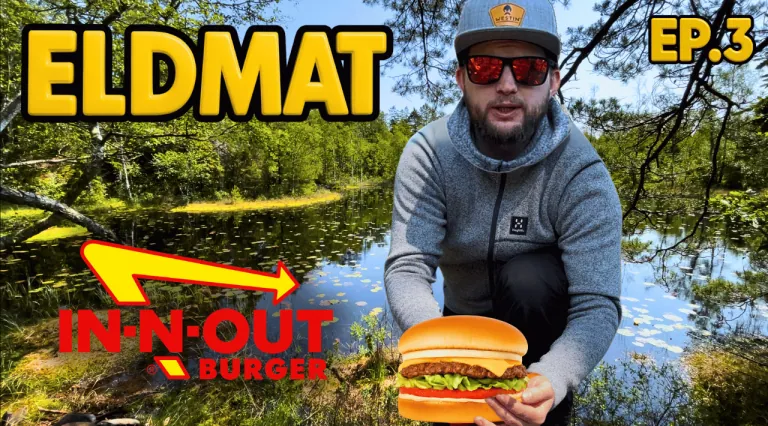 Mies seisoo järven rannalla pidellen hampurilaista In-N-Out Burgerista.