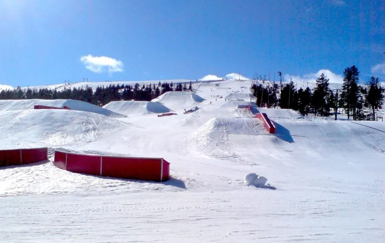 Schneebedeckte Pisten mit Rampe und Hindernissen zum Skifahren bei sonnigem Wetter. Skipark