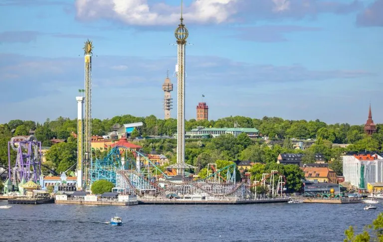 Outdoor-Vergnügungspark am Wasser mit Fahrten und üppiger Umgebung.