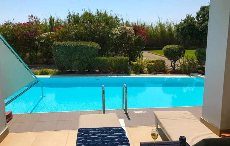 Forfriskende pool med liggestole og frodige omgivelser.