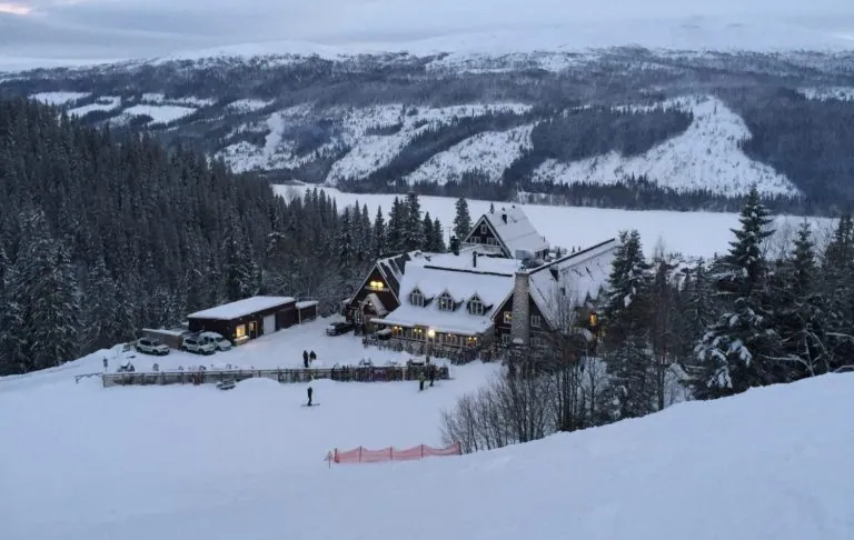 Fjällstuga omgiven av snö och träd i en vinterlandskap.