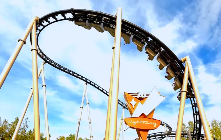Een achtbaan die omhoog buigt met een oranje bord op de voorgrond.