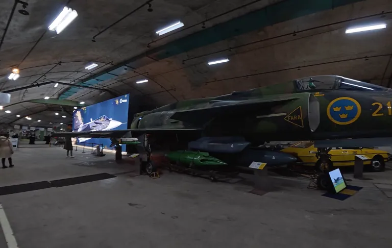 Ett militärflygplan i en hangar, med svenska lösningar på lackeringen.