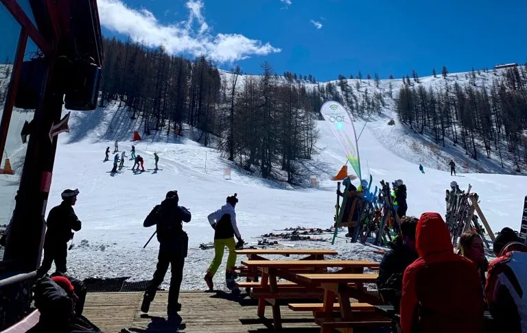 Skifahrer auf einer verschneiten Piste mit einigen Liften im Hintergrund.