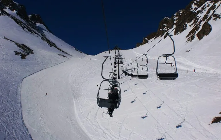 Chairlift on a snow-covered mountain under a clear blue sky.