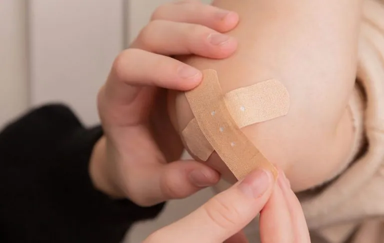Ranka uždeda tinką ant kelio.