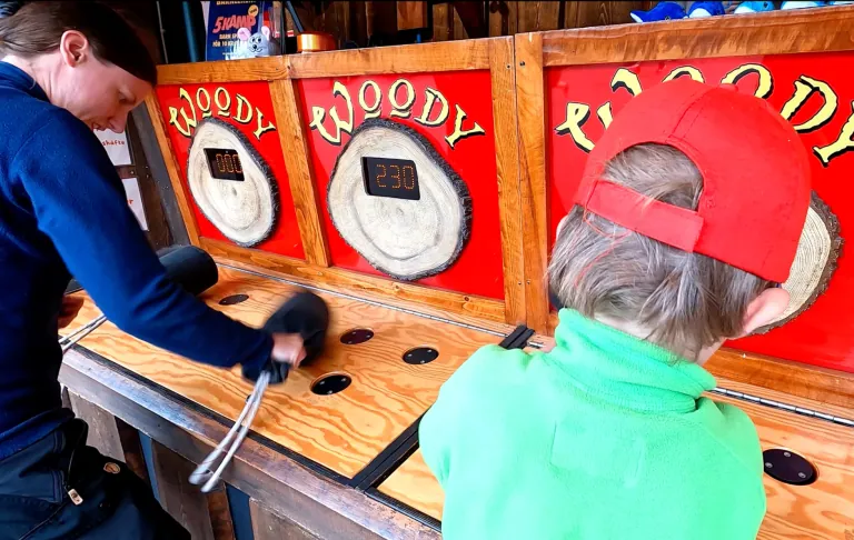 En vuxen och ett barn spelar ett spel där de slår på plattor med klubbor.