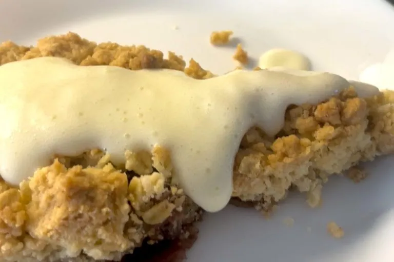 Et stykke gooey kake med en kremet saus på toppen.