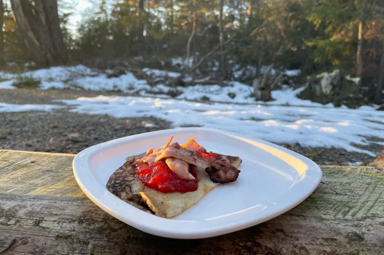 Pannekaker med bacon og jordbærsyltetøy i skogen på en vinterutflukt.