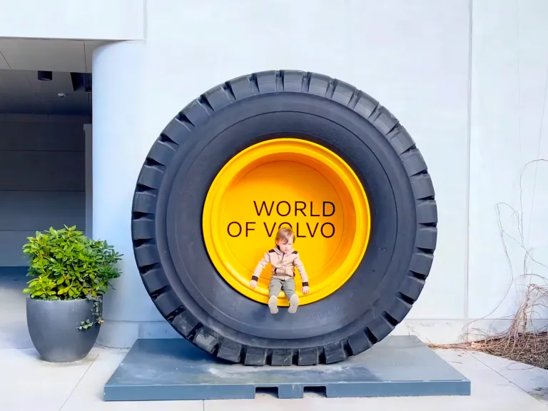 Велика конструкція шин Volvo з текстом «WORLD OF VOLVO» і маленькою фігуркою, що сидить в ній.