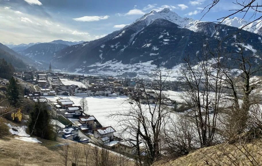 View of snow-covered mountains and a village in the valley under a clear sky.