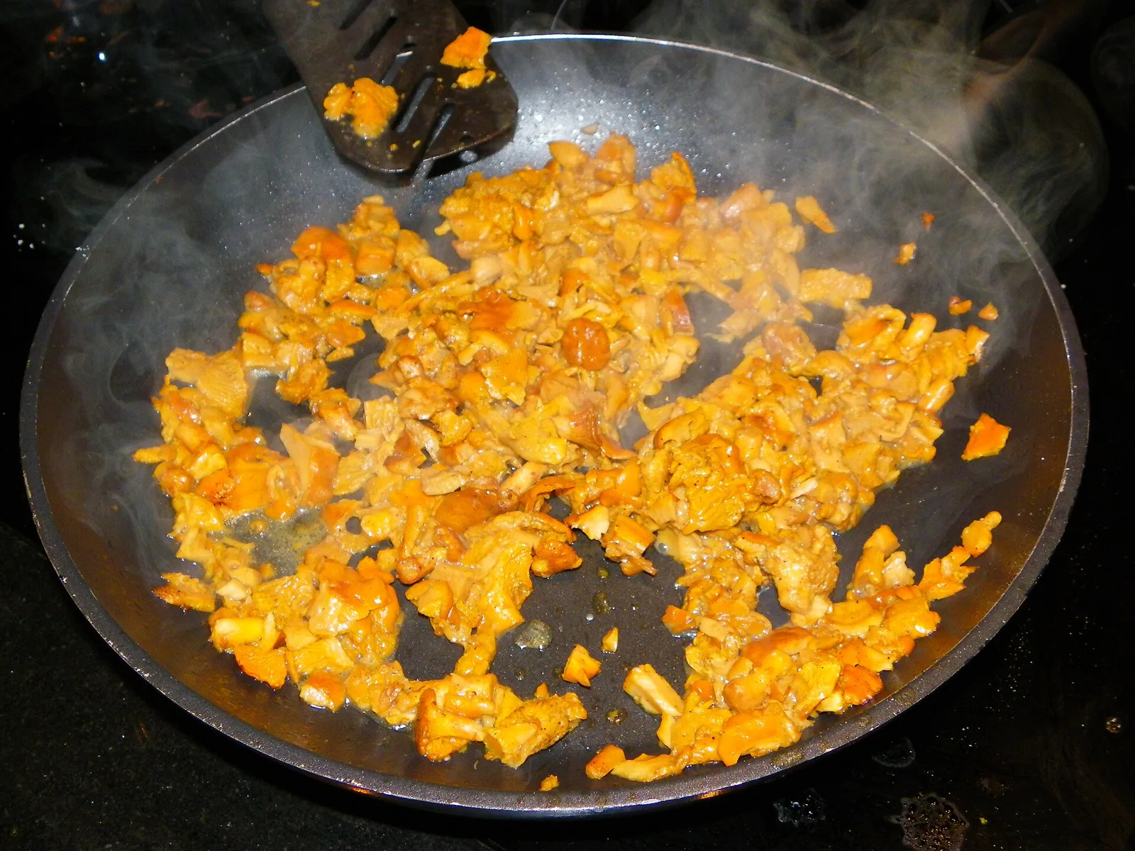 Kuldsed kukeseened praadivad mustas pannis, auru tõustes.