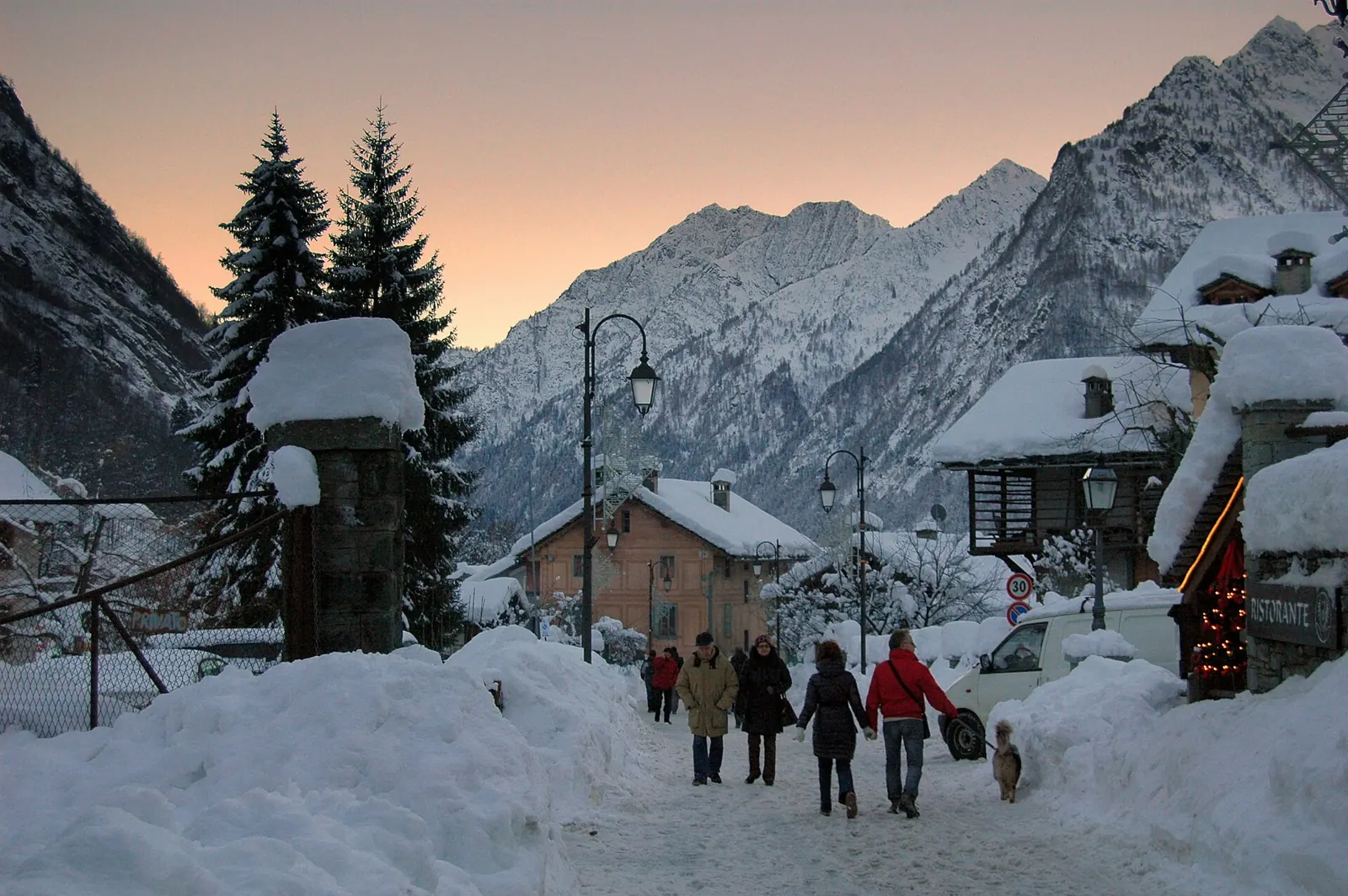 Alagna Valsesia ciemata iela, kas atrodas pie krēsla ar Walser mājām, ielu lampām un sniega kalniem fonā