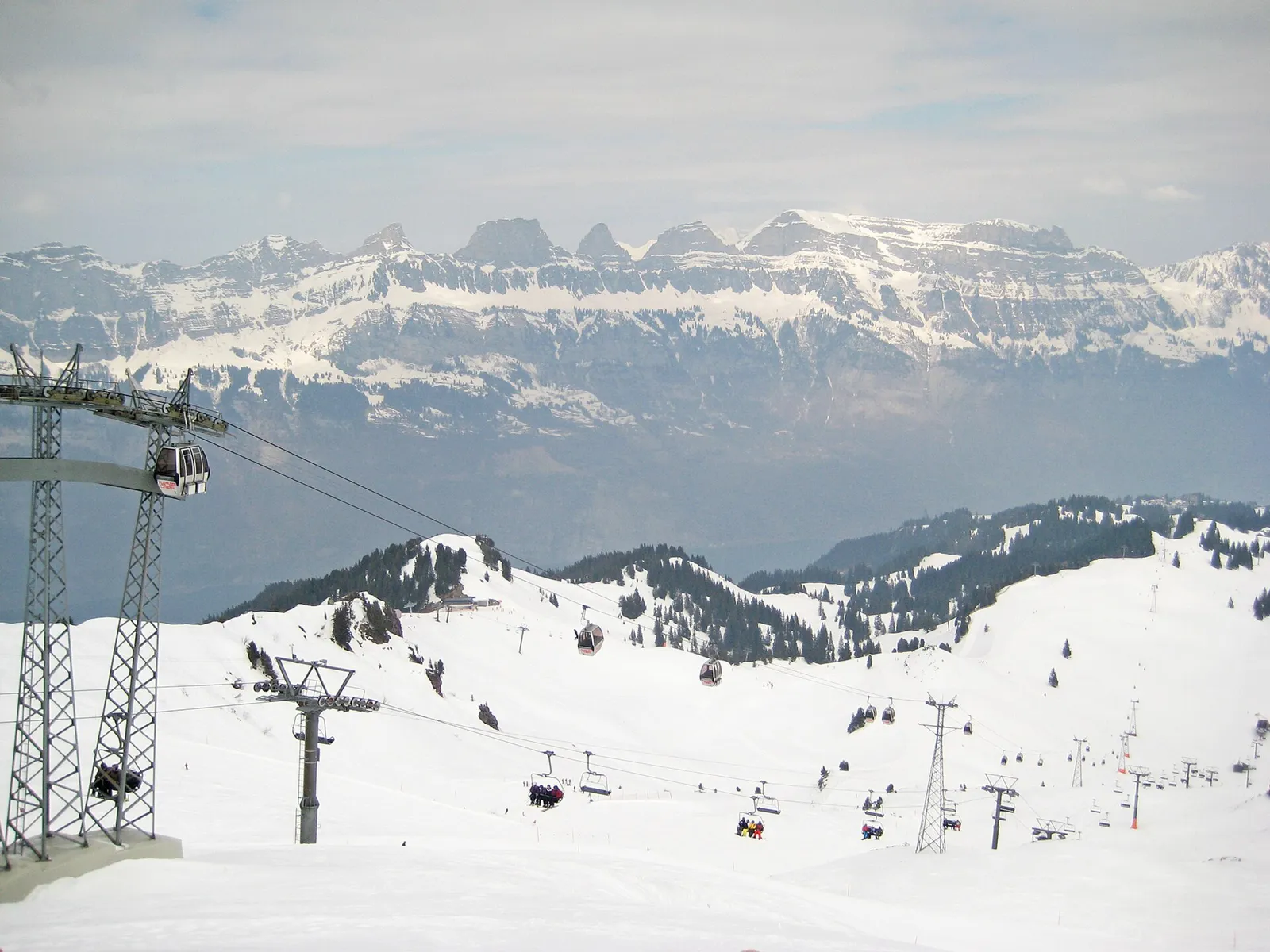 Verschneite Pisten und Lifte am Flumserberg vom Maschgenkamm aus gesehen, mit Gondeln, Sesselliften und der Bergkette der Churfirsten im Hintergrund