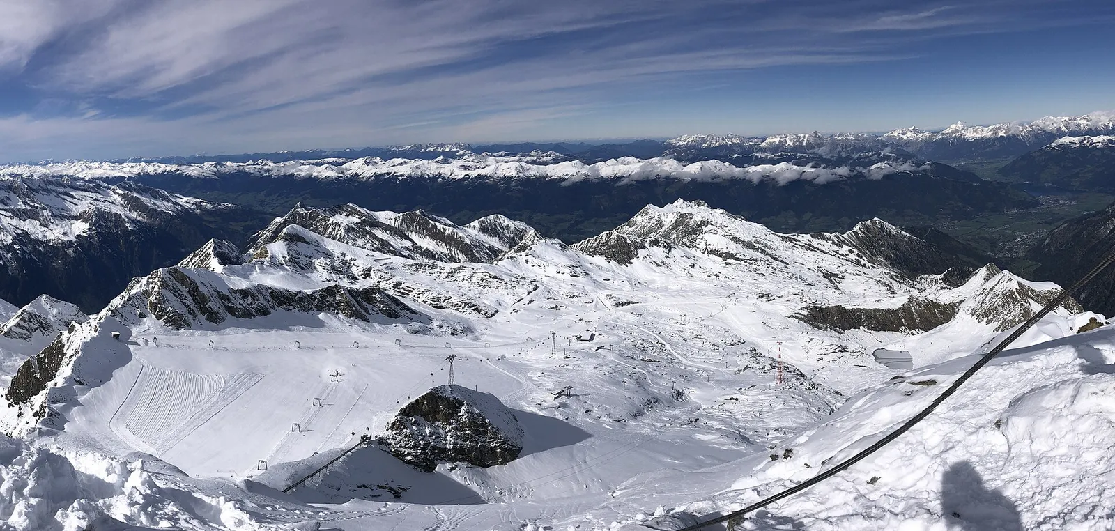 Näkymä Kitzsteinhornin huipulta jäätikön hiihtoalueelle hisseineen ja kunnostettuine rinteineen sekä kaukana oikealla järven rannalla oleva Zell am See