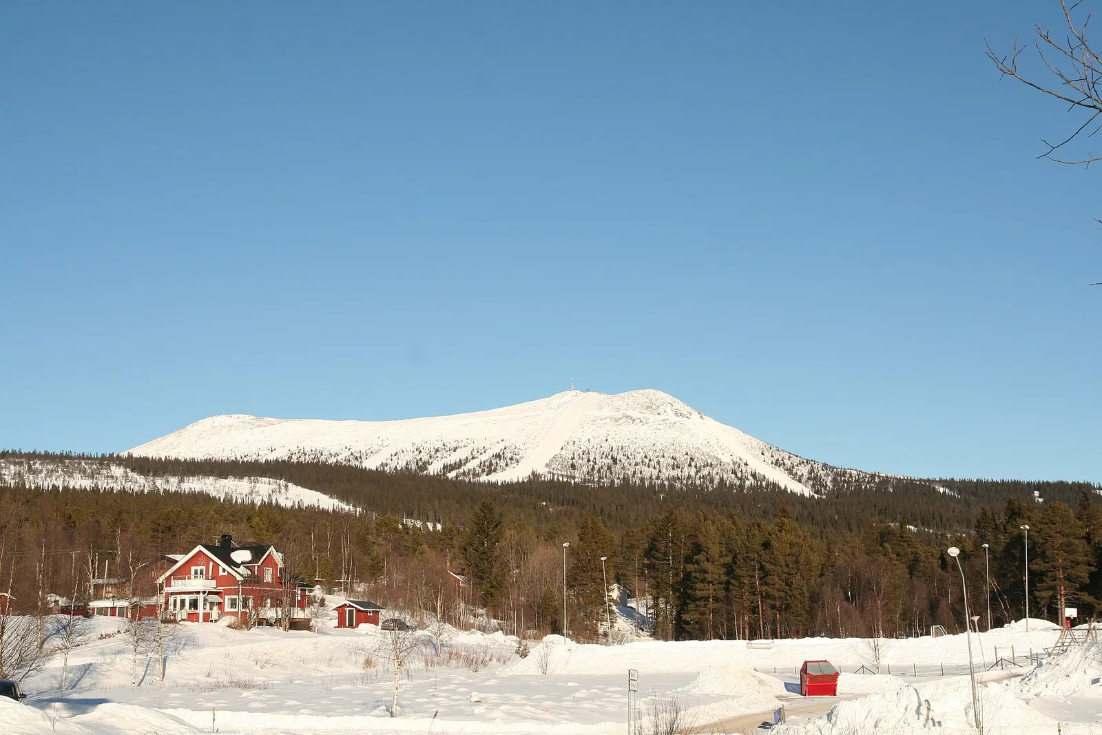 Det snötäckta fjället Hovärken med nedfarterna synliga ovanför skogen