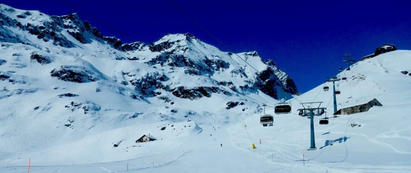 Krēslu pacēlājs un pacēlāju stacija augstu kalnos un klintīs zem tumši zilajām debesīm Monterosā Ski