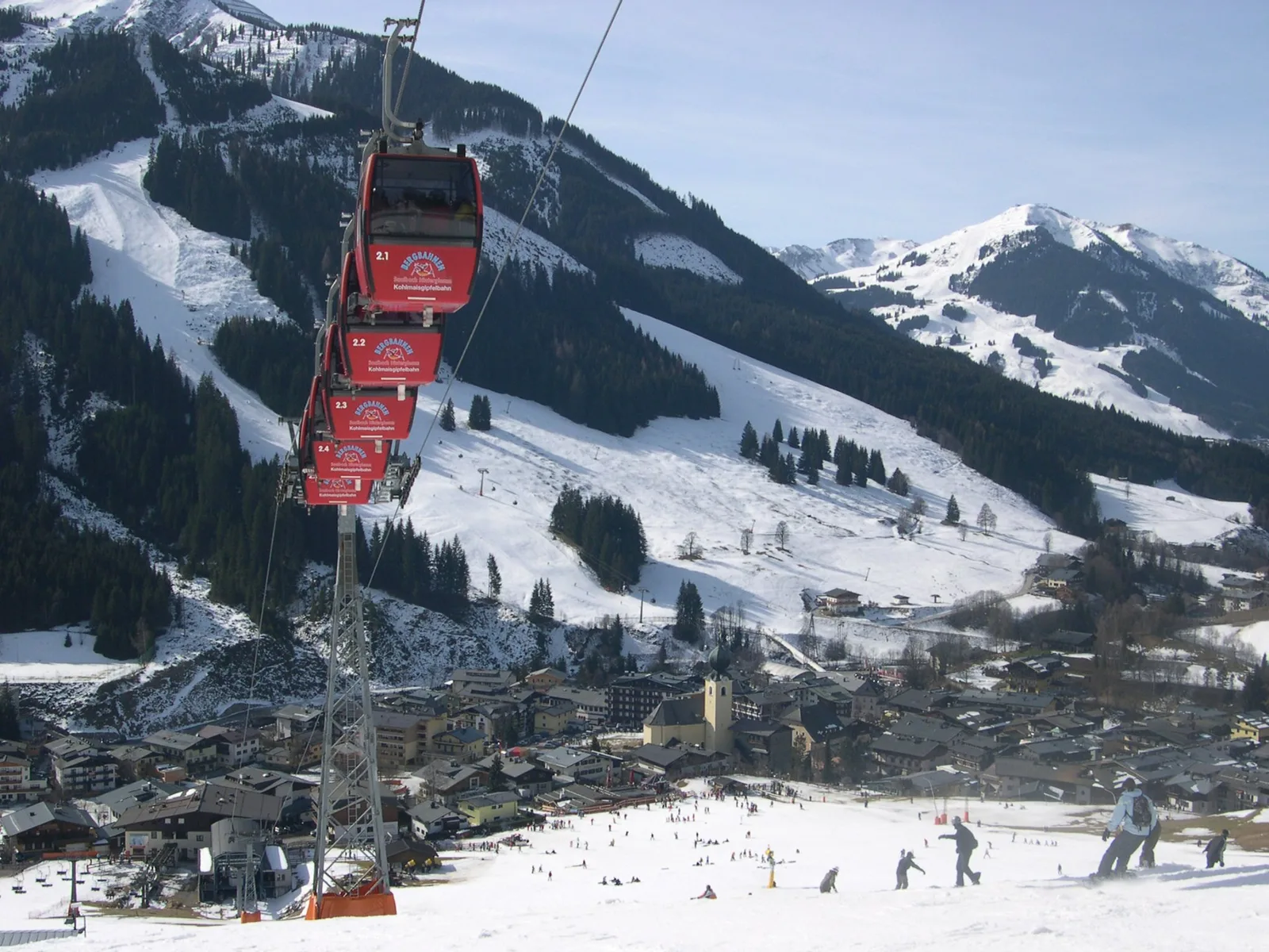 Kohlmaisbahns røde gondoler over Saalbach, med snedækkede pister og landsbyen nede i dalen