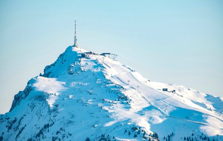 Snötäckt bergstopp med en utsiktstorn på toppen.
