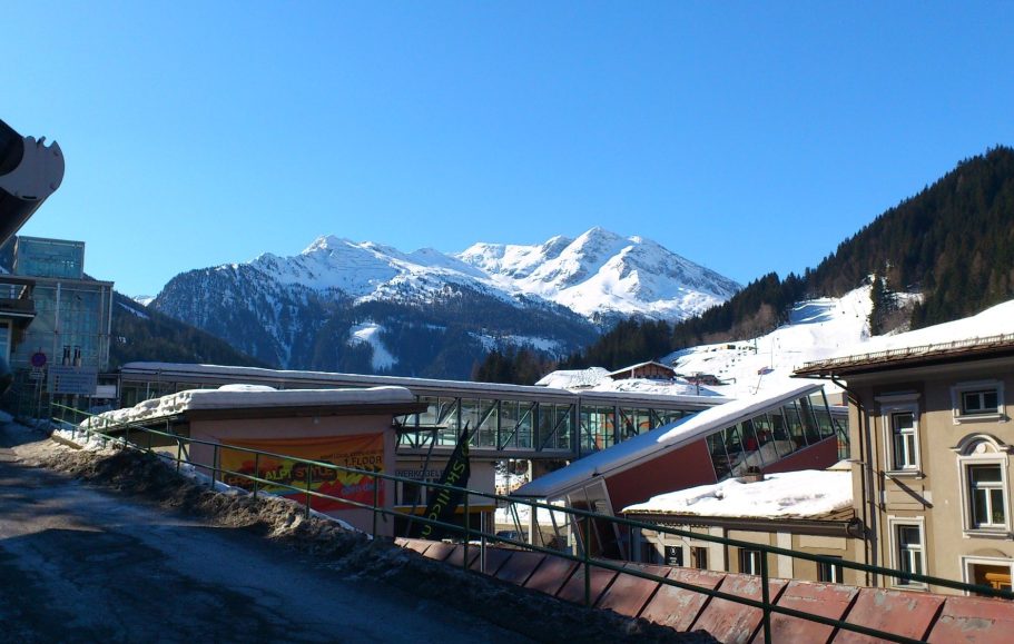 Utsikt över snötäckta alpberg och byggnader i en vinterlandsby.