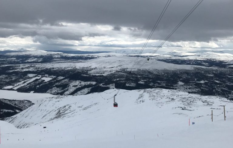 Utsikt över snöklädda fjäll och åres kabinbana/gondolbana under ett molnigt himmel.