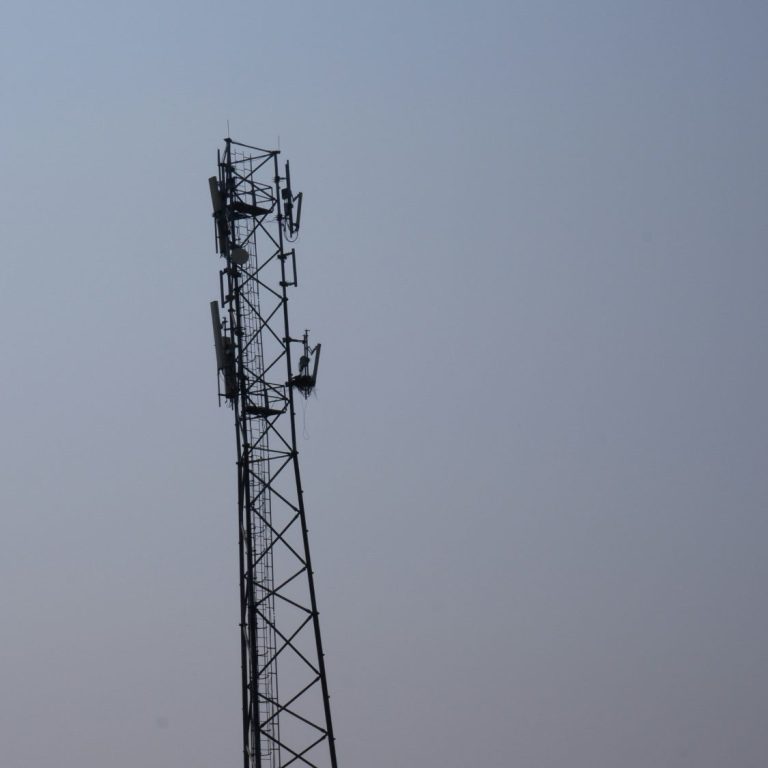 Mobilmast på en stålstruktur mot en klar himmel.
