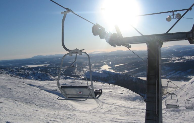Åre 1000 meters liften Stolslift med sol i bakgrunden och snöiga landskap nedanför.