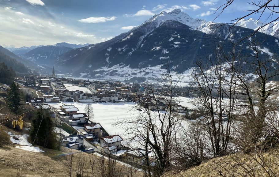 Utsikt över snöklädda berg och en by i dalen under en klar himmel.