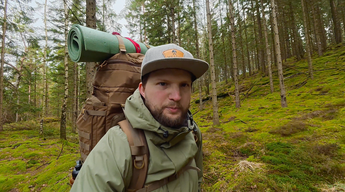 Johannes i skogen Man med ryggsäck och liggunderlag vandrar genom en skog.