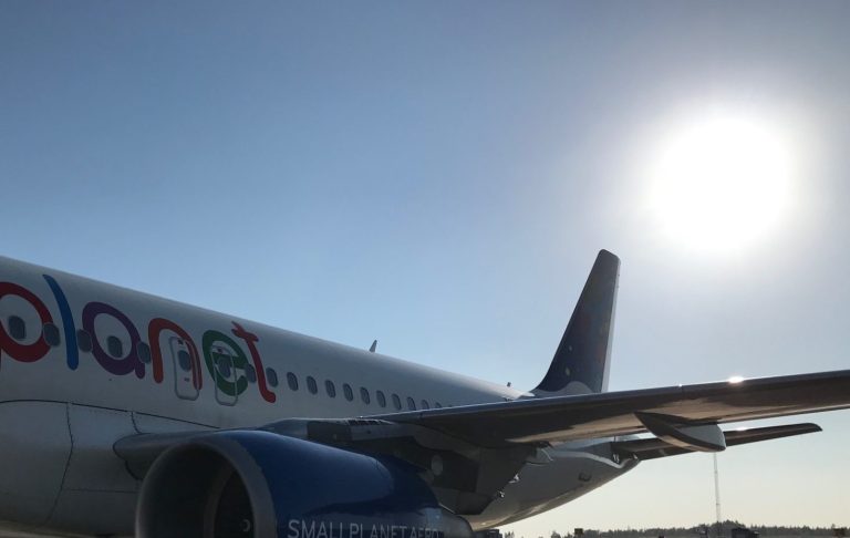Ett flygplan med sol bakom och klar himmel.
