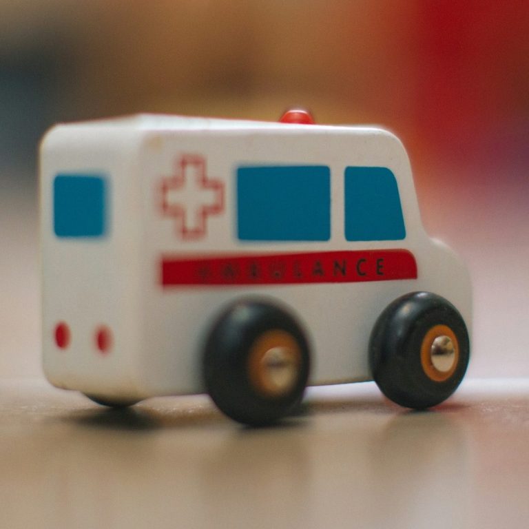 En liten leksaksambulans med röd och blå detaljering.