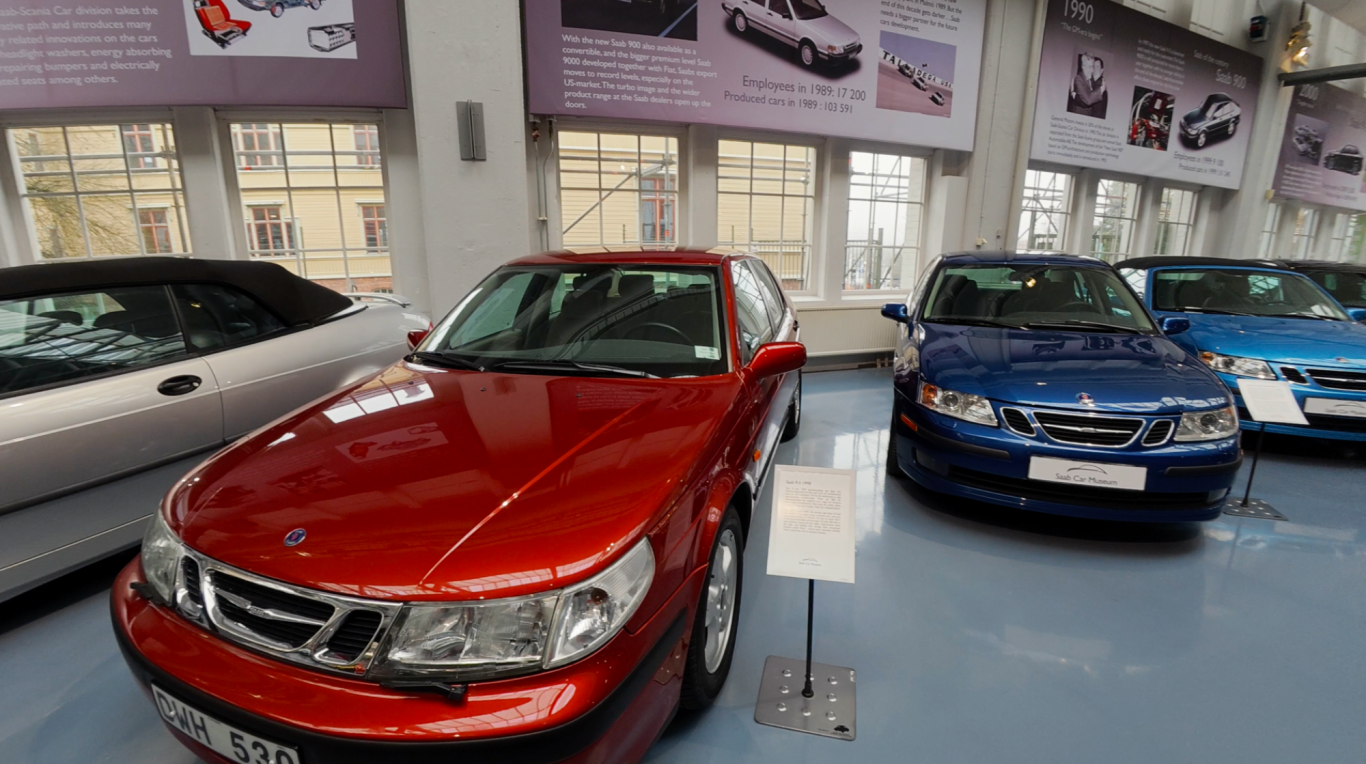 Saab bilar Röd bil i en bilutställning med flera andra bilar i bakgrunden.