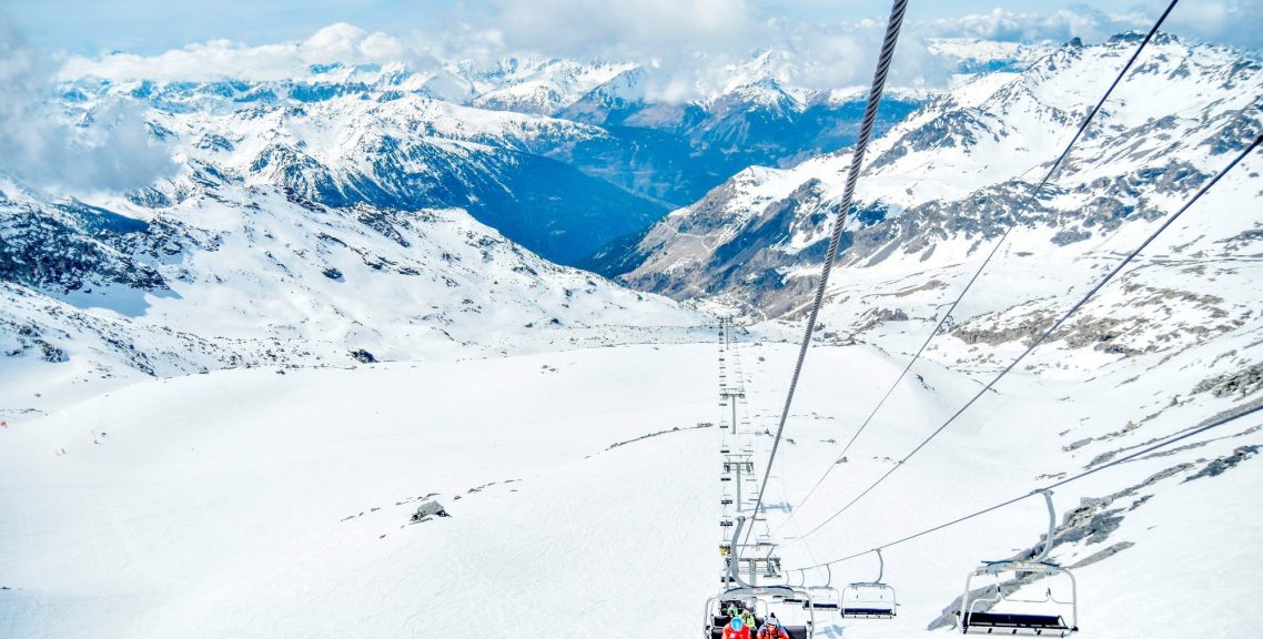 Utsikt från en skidlift över snöklädda berg och dalar.
