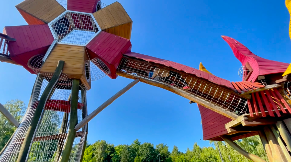 Vallarnas Friluftsområde Lekplatsen Färgglad lekplats med röd och gul struktur och trappor i en park.