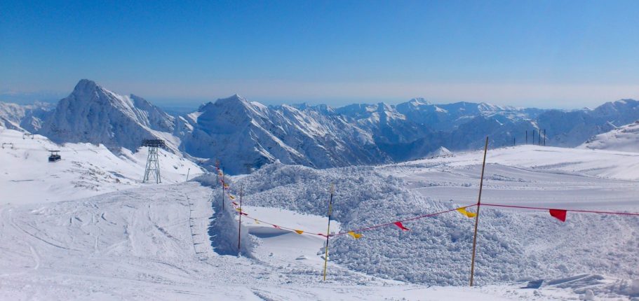 Skidbacke med stolslift och snöklädda fjäll i bakgrunden.