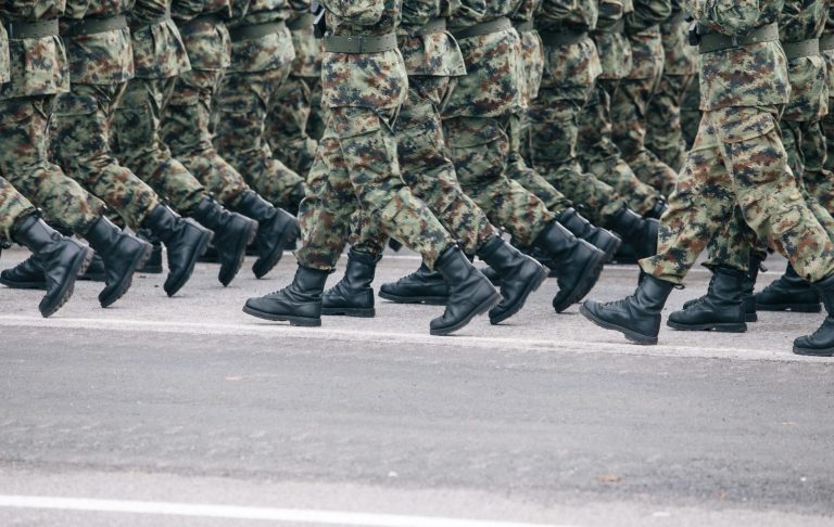 Soldater i kamouflageuniformer marscherar i takt med svarta kängor.