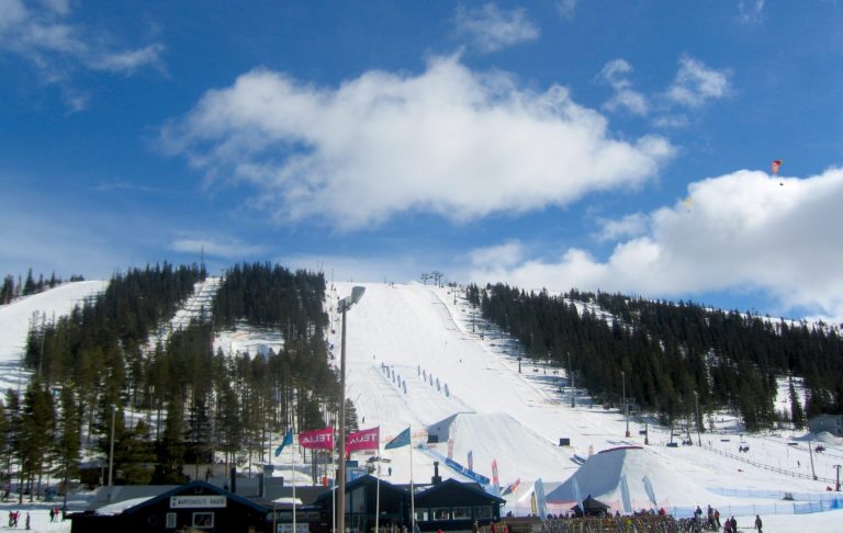 Snöklädda backar med lifter och molnig blå himmel.