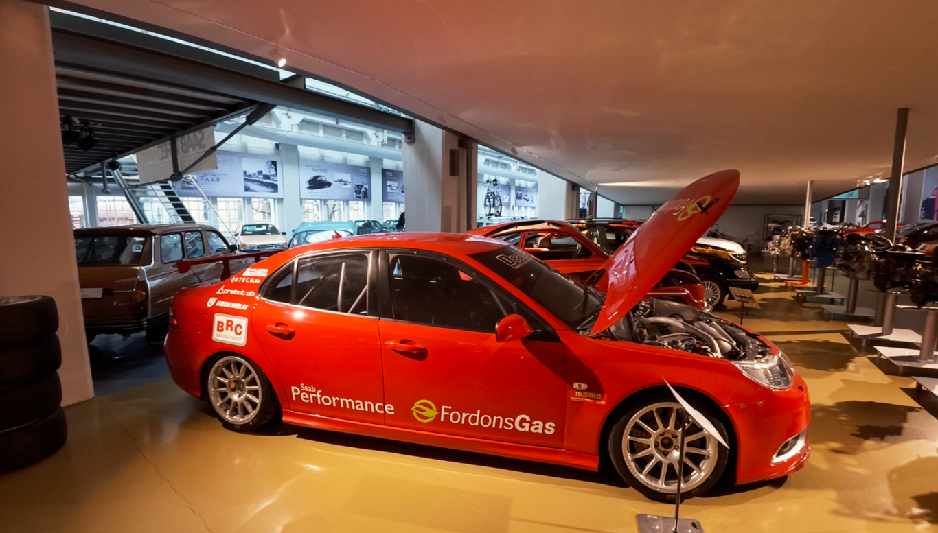 Saab Fordonsgas Röd tävlingsbil med öppen motorhuv i en bilutställning.