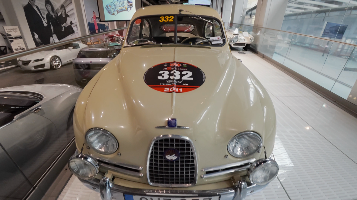 Rallybil En beige gammal bil med en svart nummerskylt på framsidan.