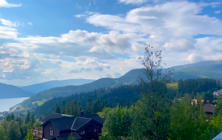 Utsikt över kullar och sjöar under en ljusblå himmel med några moln.