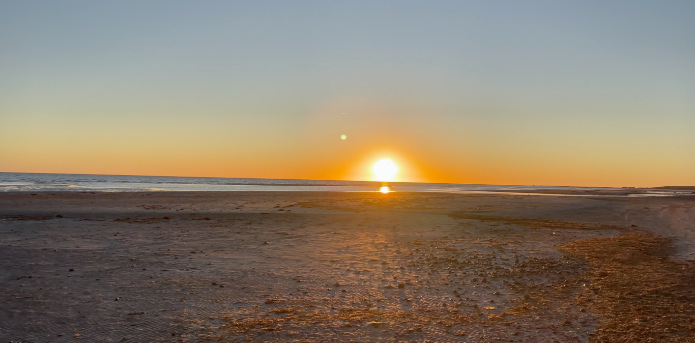 Solnedgång på Stranden Solnedgång över havet med en klar himmel och reflektioner på vattnet.