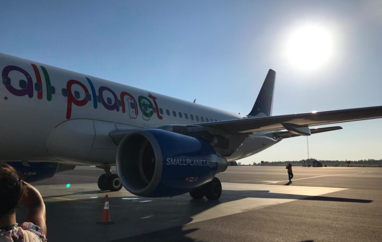 Ett flygplan med texten "all planet" står på en flygplats under en solig himmel.