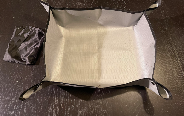 En fyrkantig, vikbar förvaringslåda i grå och svart med handtag.