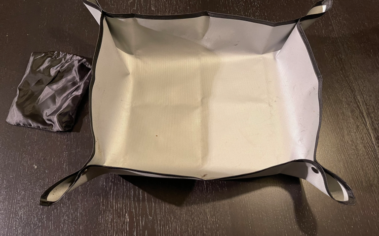 En svart och vit vikbar förvaringslåda med handtag, placerad på ett mörkt bord.