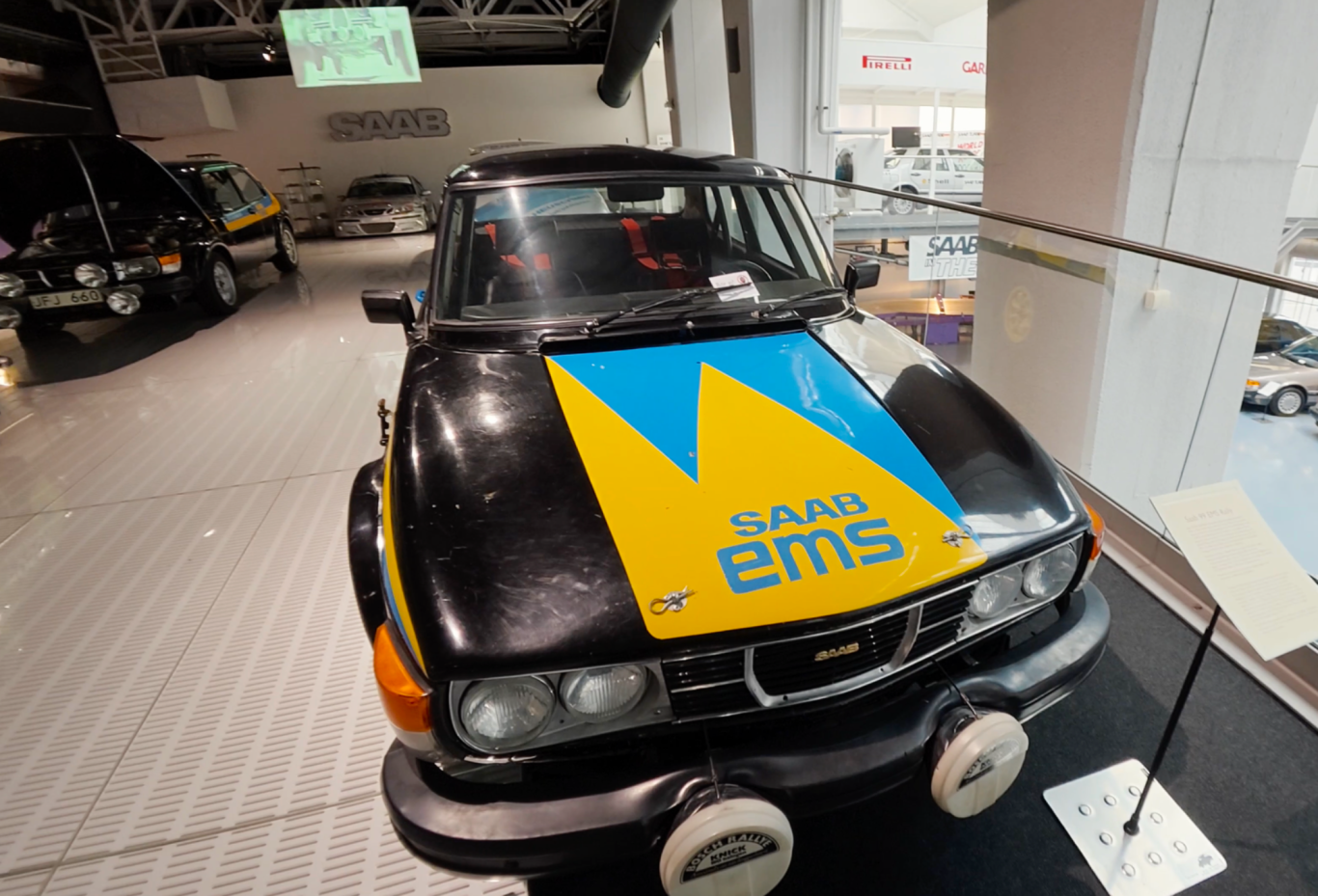 Rallybil Svart bil med gul och blå dekor, modell Saab med texten "ems" på huven.