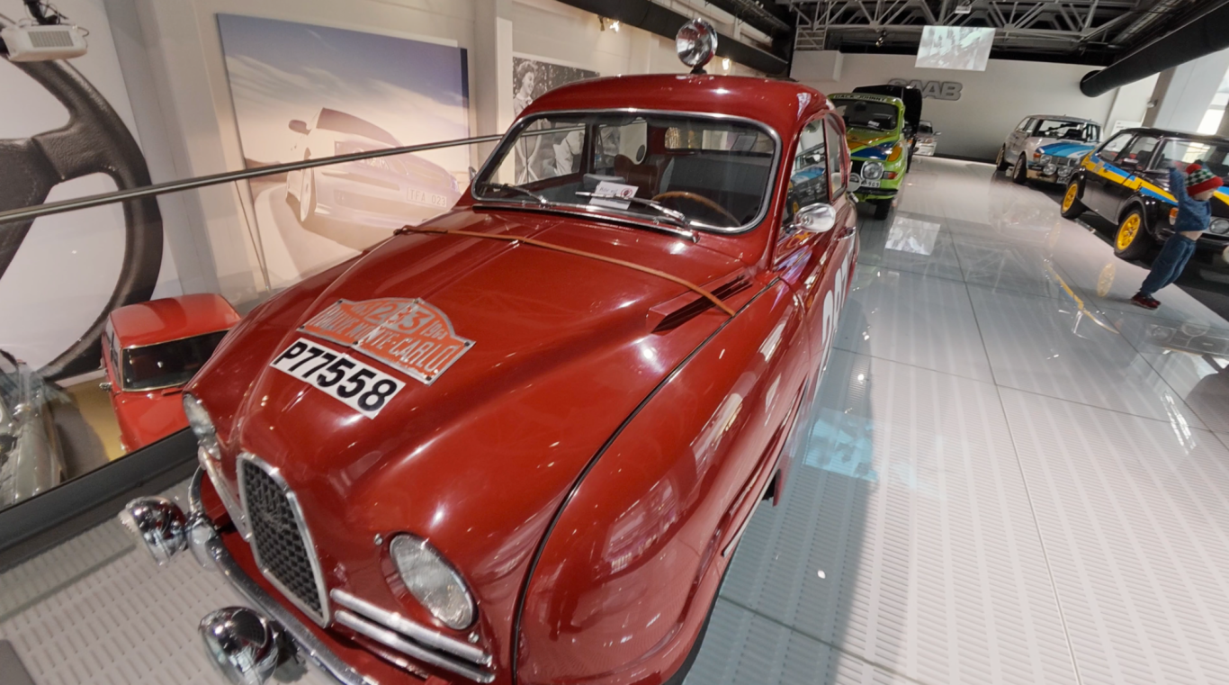 Rallybil Röd klassisk bil utställd i ett museum, omgiven av andra fordon.